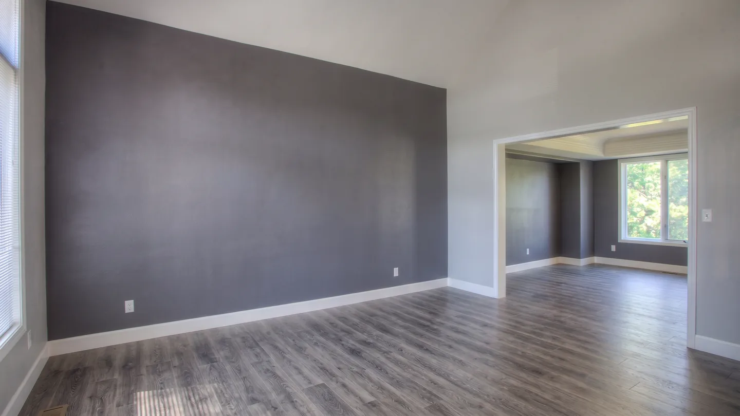 The same living room with every movable piece gone — the accent wall, skirting, floor and the opening through to the dining room unchanged